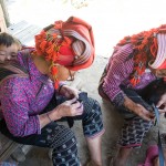 Red Dao woman sewing with child on her back